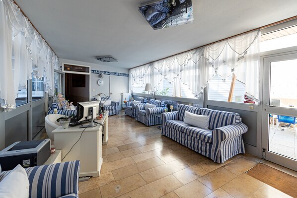 A spacious living area with striped sofas, a white desk with a computer, and a large window with curtains. - Hotel Höhn (Ruedesheim am Rhein)
