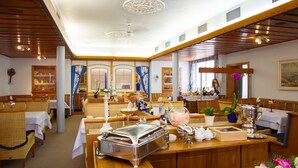 A hotel dining area with wooden furniture, a buffet setup, and a bar area. - Hotel Höhn (Ruedesheim am Rhein)