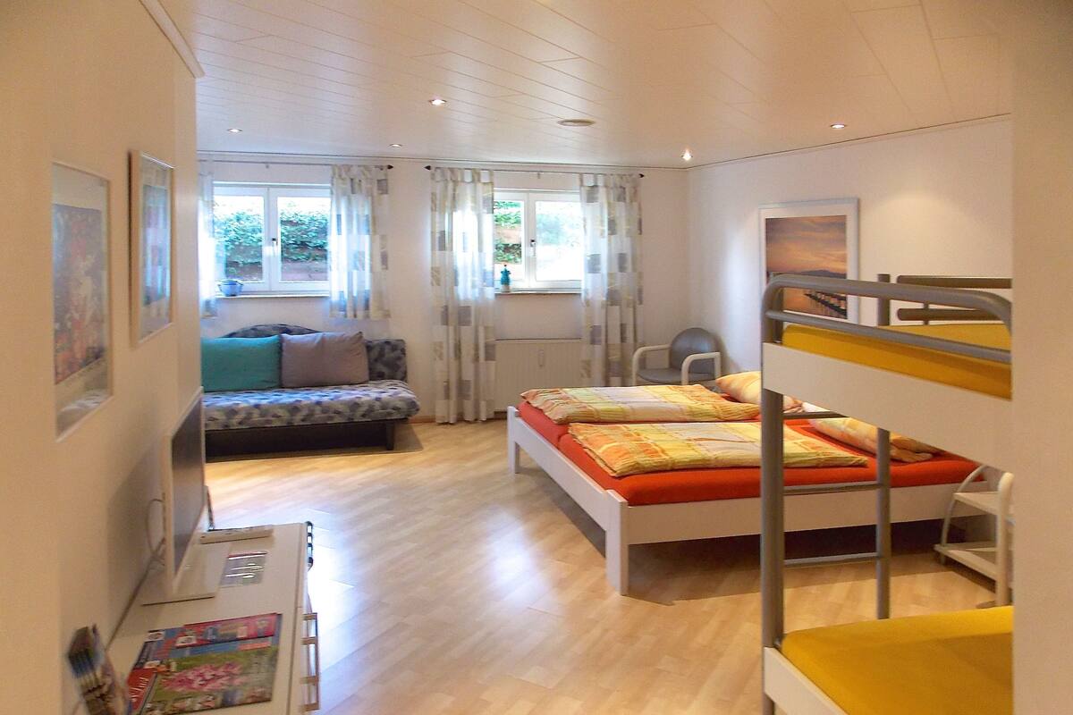 A bedroom with bunk beds, a sofa, a desk, and a window with curtains.