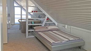 A compact, loft-style bedroom with a bed, a small table, and a chair. - Gästehaus Alba (Rust)