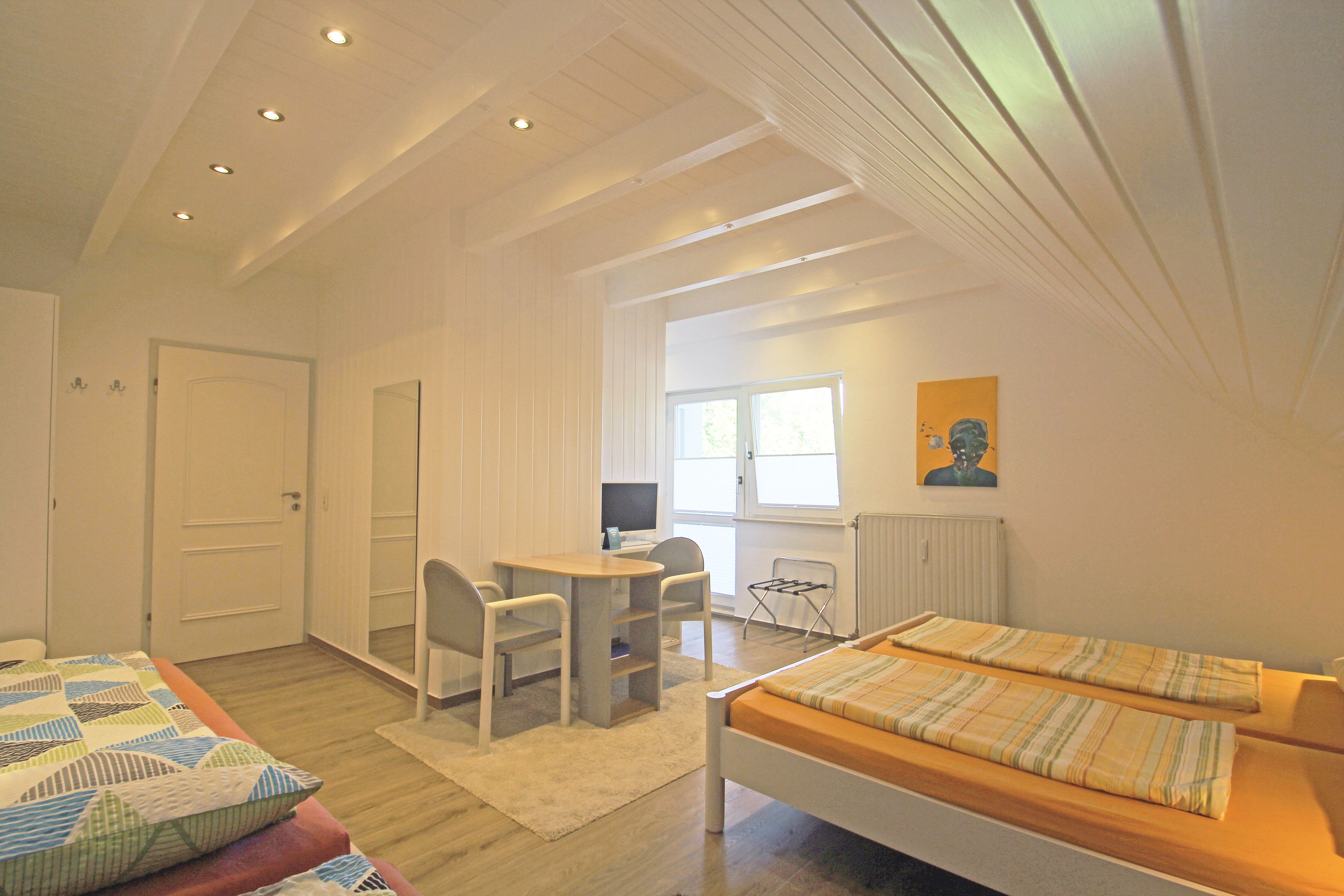 Une chambre à coucher avec un lit, un bureau et une chaise. Il y a une fenêtre donnant sur l’extérieur.