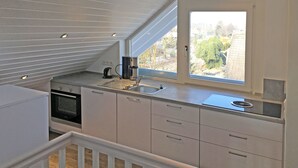 A modern kitchen with a built-in oven, a coffee maker, and a window with a view of the outside. - Gästehaus Alba (Rust)