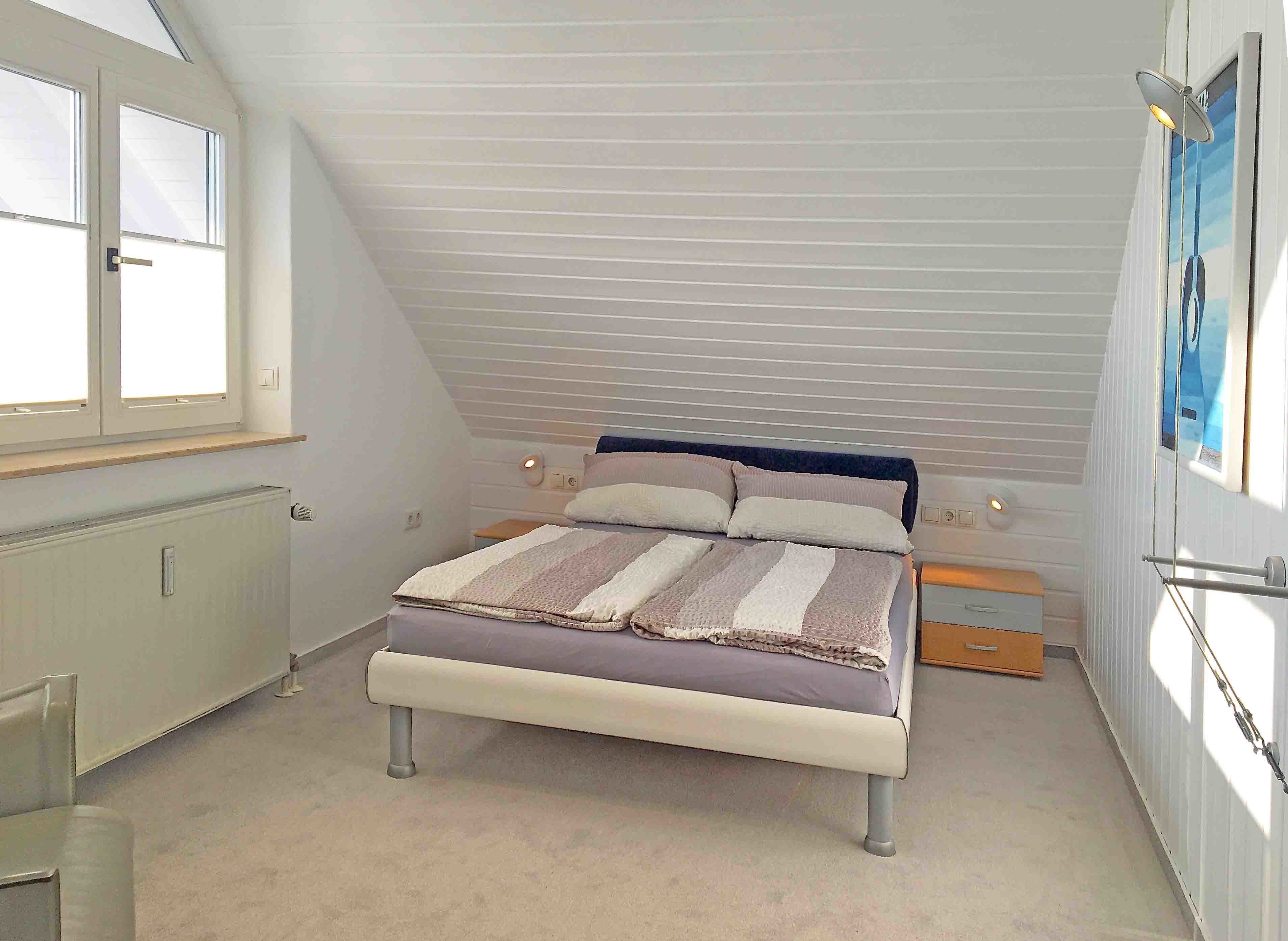 A bedroom with a bed, a window, and a radiator.