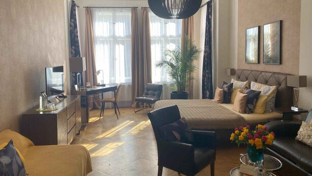A well-lit hotel room with a bed, a desk, a chair, a sofa, and a coffee table. - mittendrin - Boutique Hotel Berlin (Berlin)
