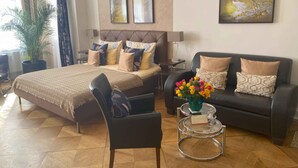 A hotel room with a bed, a sofa, a chair, a small table with a vase of flowers, and artwork on the walls. - mittendrin - Boutique Hotel Berlin (Berlin)