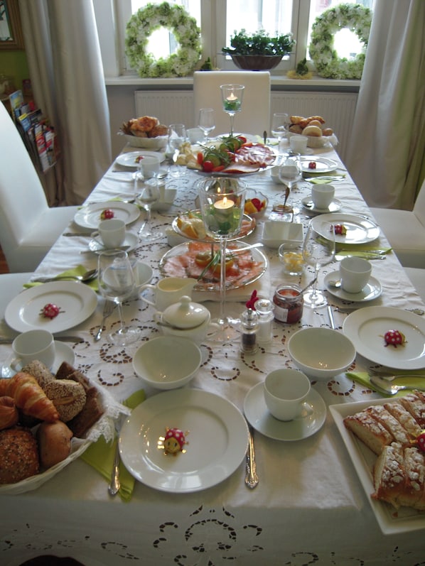 Une longue table à manger, dressée avec des assiettes, des verres et divers plats, évoquant un repas formel.