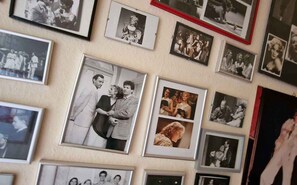 Una pared con varias fotografías enmarcadas de personas en diferentes lugares.