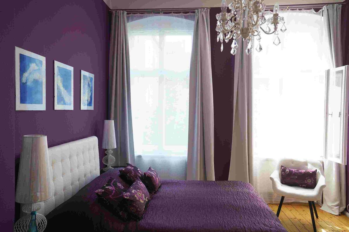 Une chambre à coucher avec un lit, une chaise, un lustre et trois tableaux encadrés accrochés au mur.