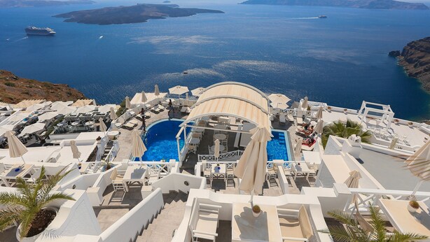 A resort with a pool area, sun loungers, and a view of the sea. - Kafieris Blue  (Santorini)