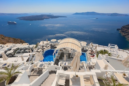 A resort with a pool area, sun loungers, and a view of the sea.