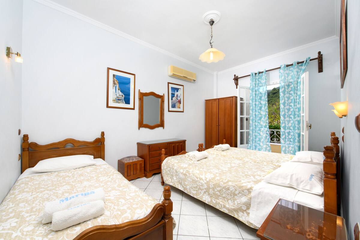 A hotel room with two beds, a wooden dresser, a mirror, and a window with curtains.