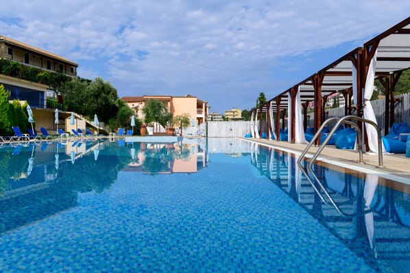 A swimming pool with blue tiles, lounge chairs, and umbrellas. - Marina Apartments (Corfu)