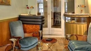 A room with a blue armchair, a wooden chair, a small round table, and a glass coffee table. - Auberge des Ecluses (Carrieres-sous-Poissy)