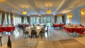 A spacious dining area with multiple round tables, red chairs, and large windows providing natural light. - Auberge des Ecluses (Carrieres-sous-Poissy)