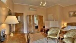 A hotel room with a bed, two armchairs, a nightstand, and a lamp. - Auberge des Ecluses (Carrieres-sous-Poissy)