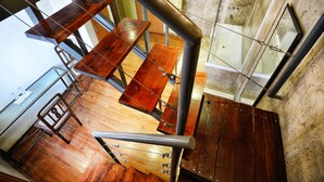 A wooden staircase with metal railings, wooden tables, and a glass partition. - La Fresque Hotel (Buenos Aires)