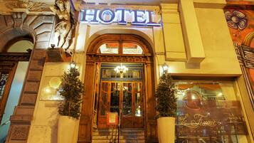 Entrada de hotel con detalles de madera labrada, un candelabro y un letrero que dice "HOTEL".