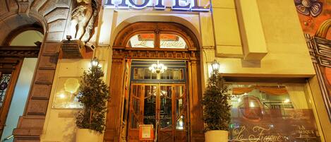 A hotel entrance with ornate woodwork, a chandelier, and a sign that reads "HOTEL."