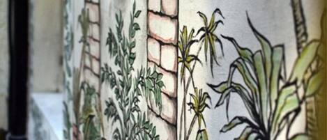 A wall with a mural of plants and a brick pattern.