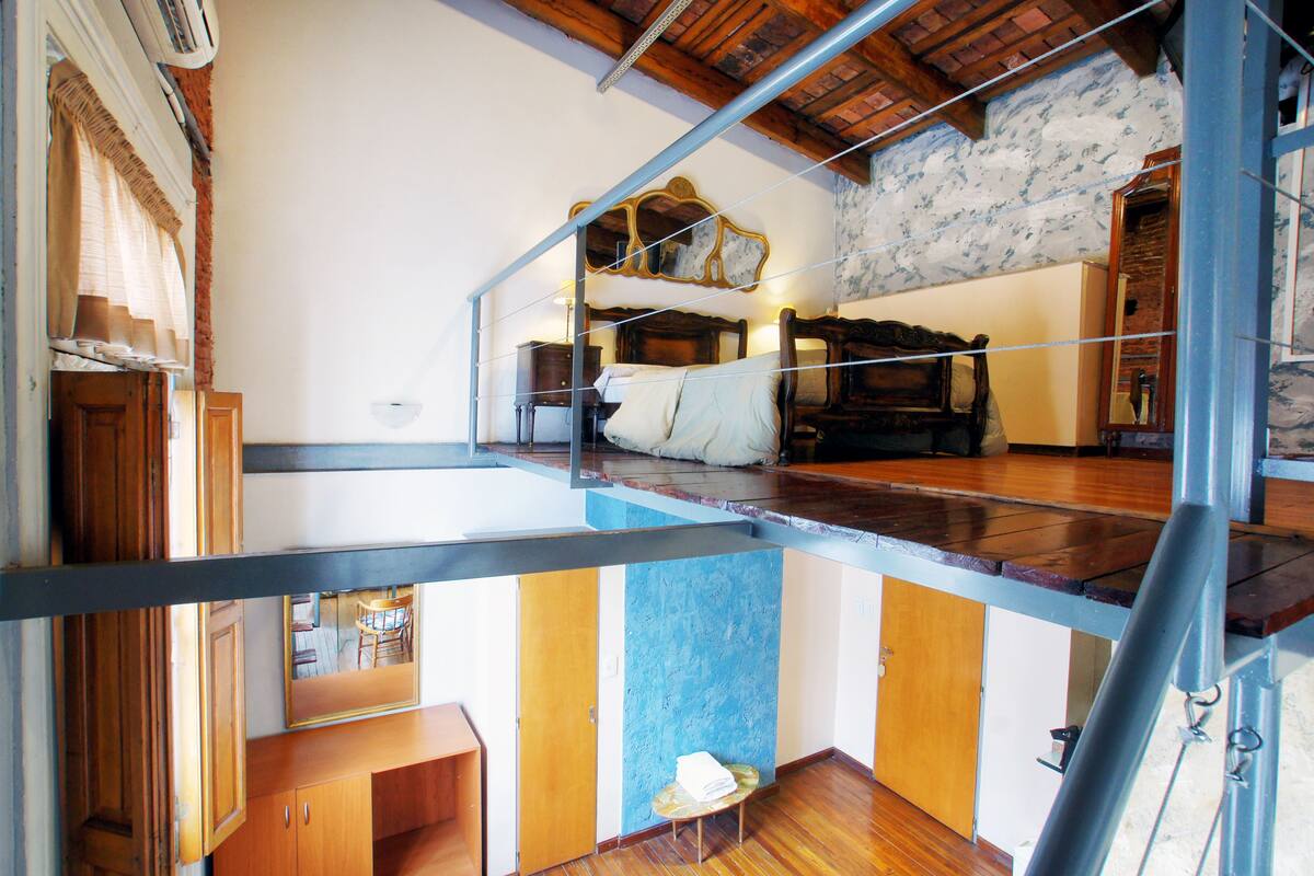 A room with a bed, a wooden cabinet, a small table with a towel, and a mirror on the wall.