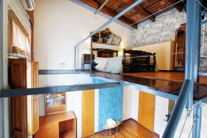 Quarto com cama, um armário de madeira, uma mesinha com toalha e espelho na parede.