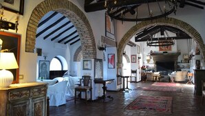Una habitación amplia con arcos de ladrillo visto, chimenea y candelabro.