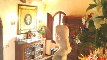A room with a stone bust, a wooden cabinet with drawers, and a framed picture on the wall.