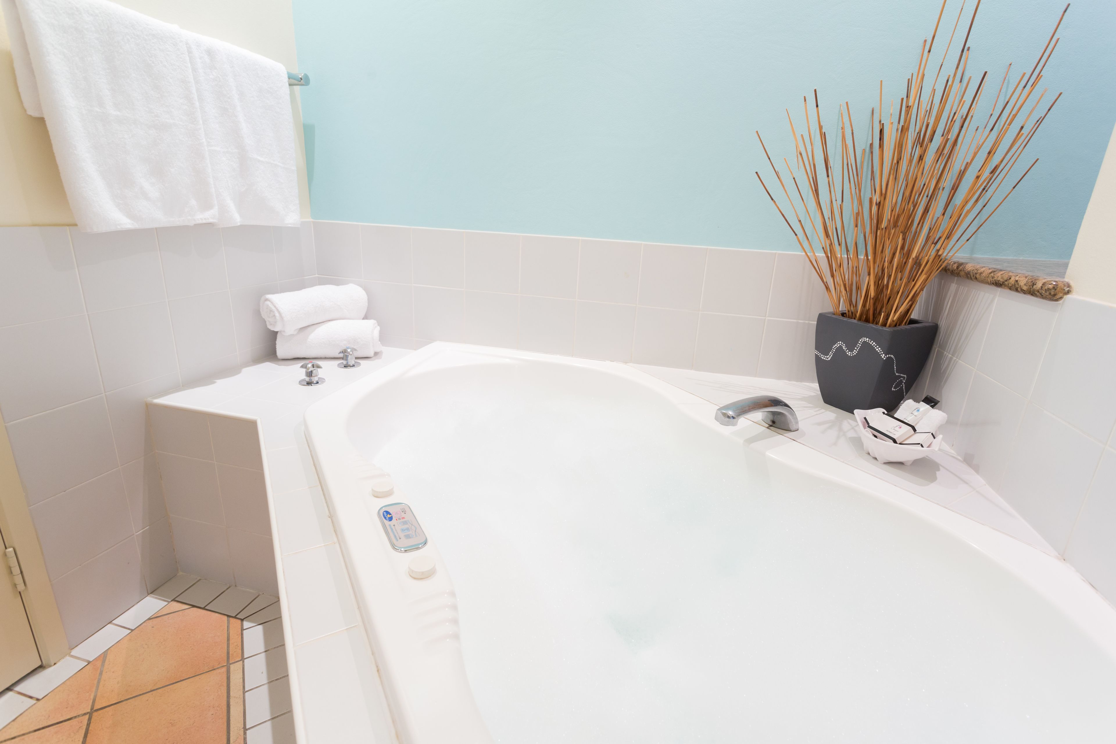 A modern bathroom with a freestanding bathtub, a towel rack, and a decorative plant.