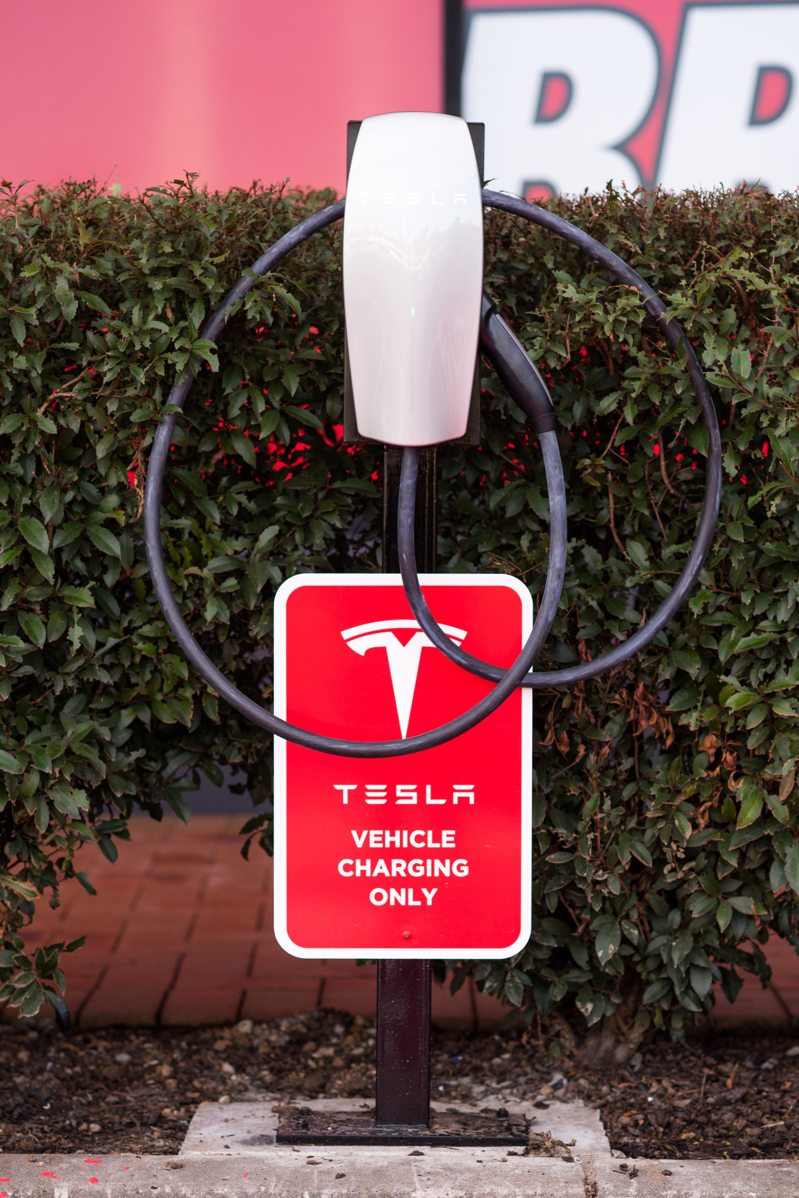 Une borne de recharge pour véhicules Tesla, avec un panneau rouge indiquant qu’elle est réservée aux véhicules Tesla.
