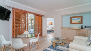 Ein modernes Wohnzimmer mit einem Glastisch, einem weißen Sofa und einem Essbereich mit einem Glastisch und Stühlen.