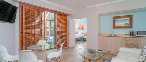 Un salón moderno con una mesa de centro de vidrio, un sofá blanco y una zona de comedor con una mesa y sillas de vidrio.