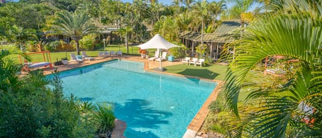 Una piscina al aire libre, sombrillas, sillones reclinables de piscina