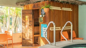 Ein Holz-Wellnessbereich mit Whirlpool, Holzwänden und einem Fenster mit Blick auf Palmen.