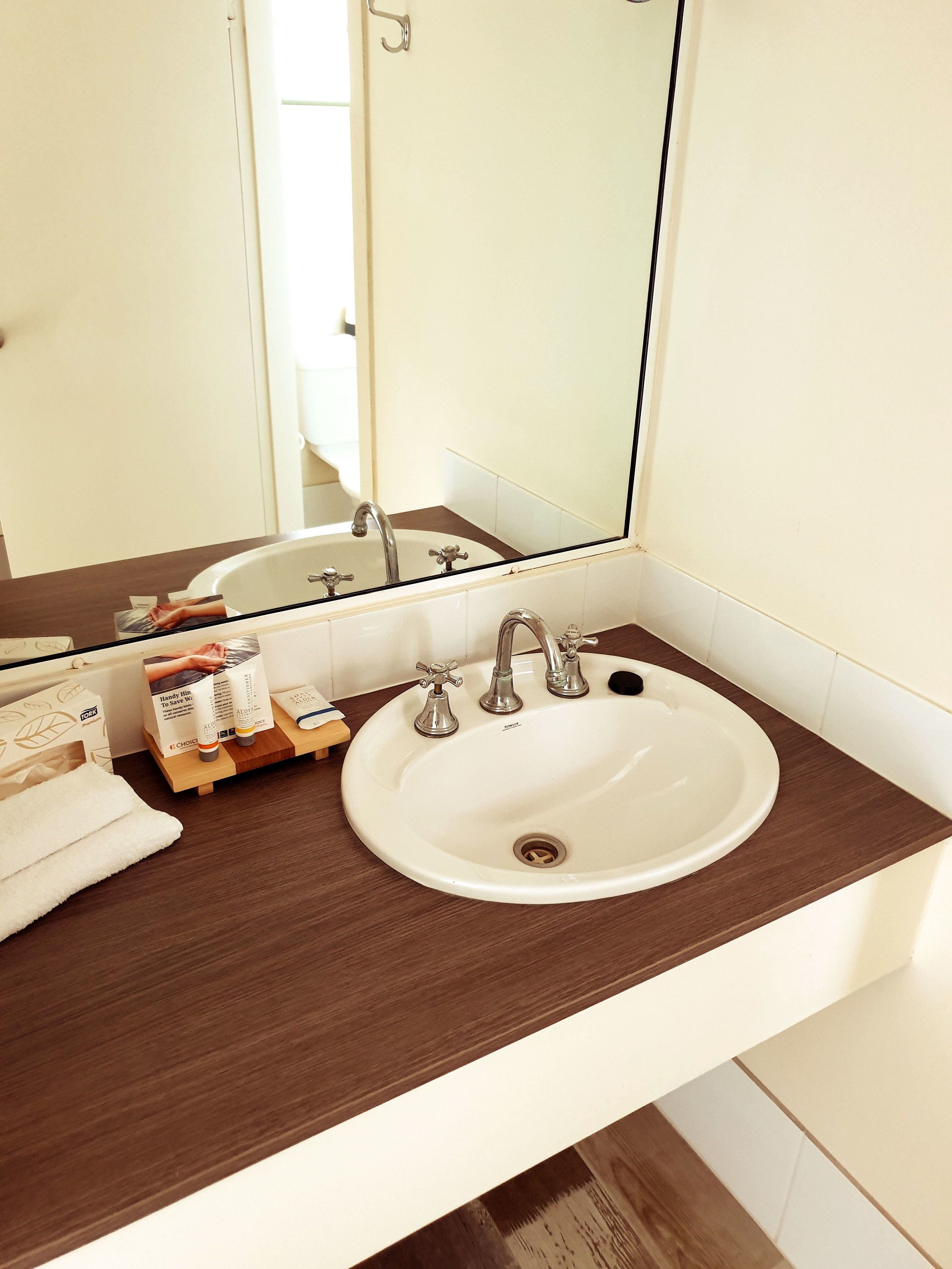 A bathroom with a white sink, a mirror, and toiletries on the counter.