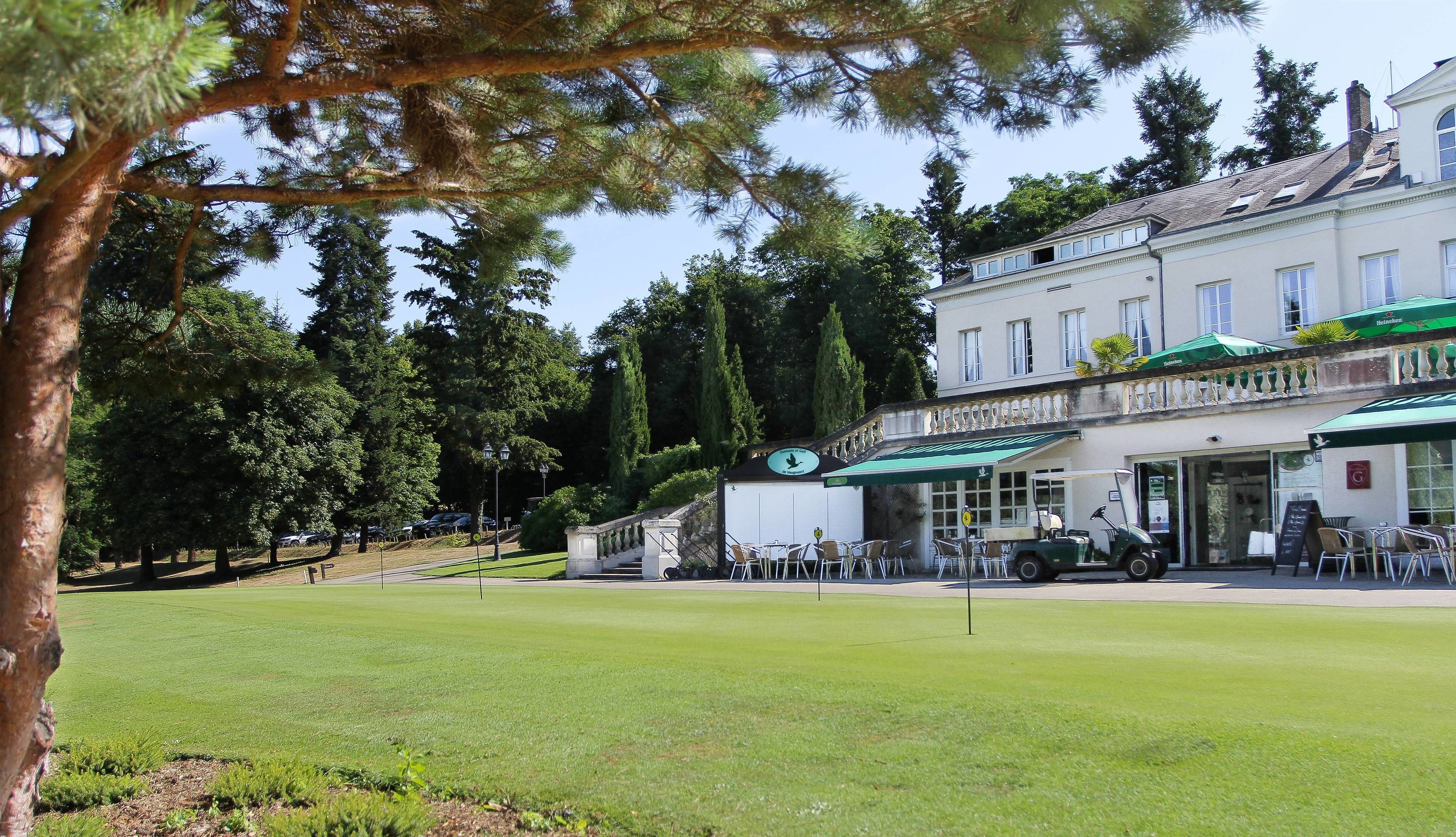 A building with a green awning, outdoor seating, and a golf cart.