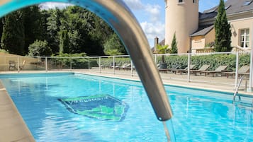 Una piscina al aire libre de temporada, sombrillas, tumbonas