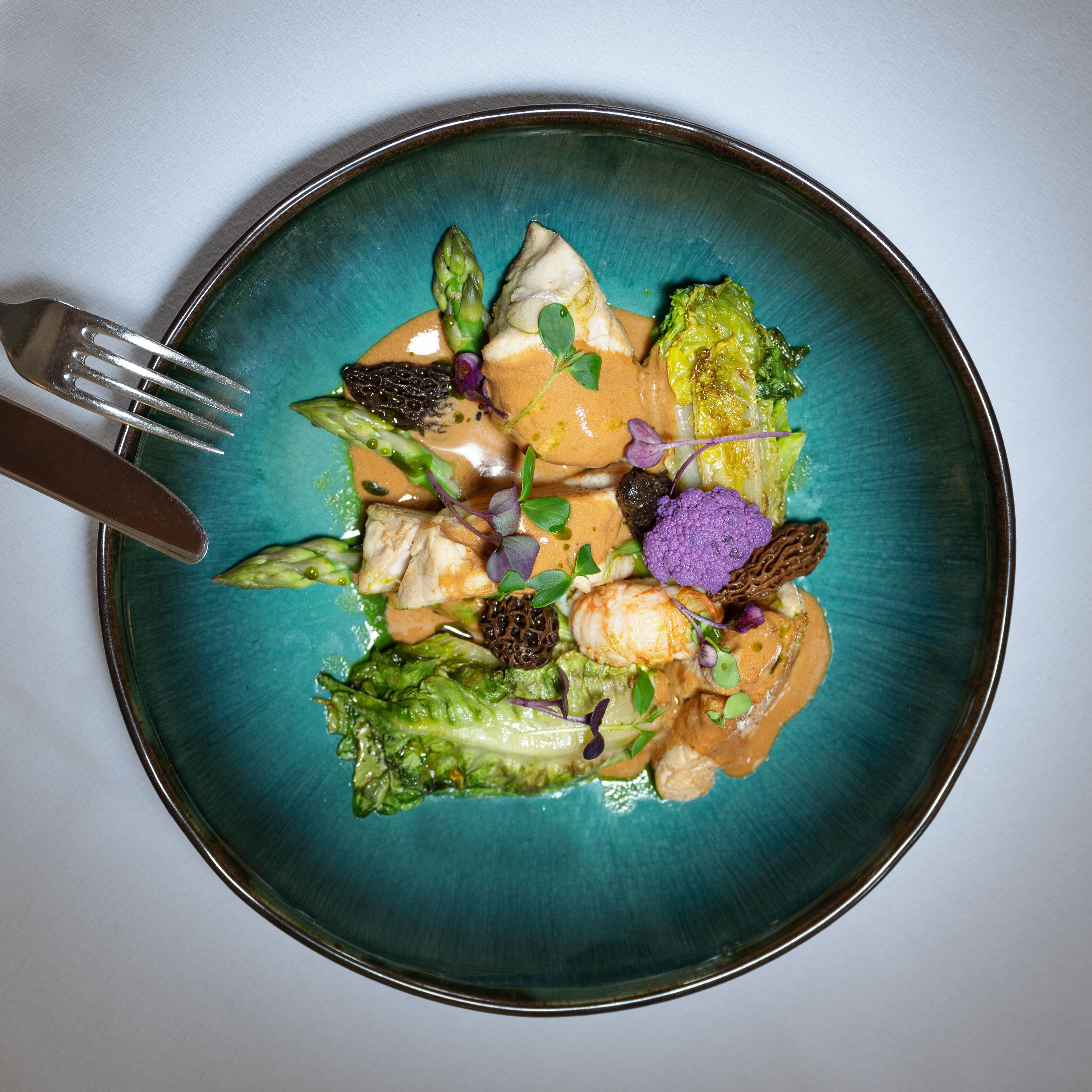A plate of food with various vegetables and a fork on the side.