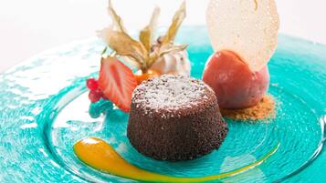 A dessert plate with a chocolate lava cake, a scoop of ice cream, and a fruit garnish.