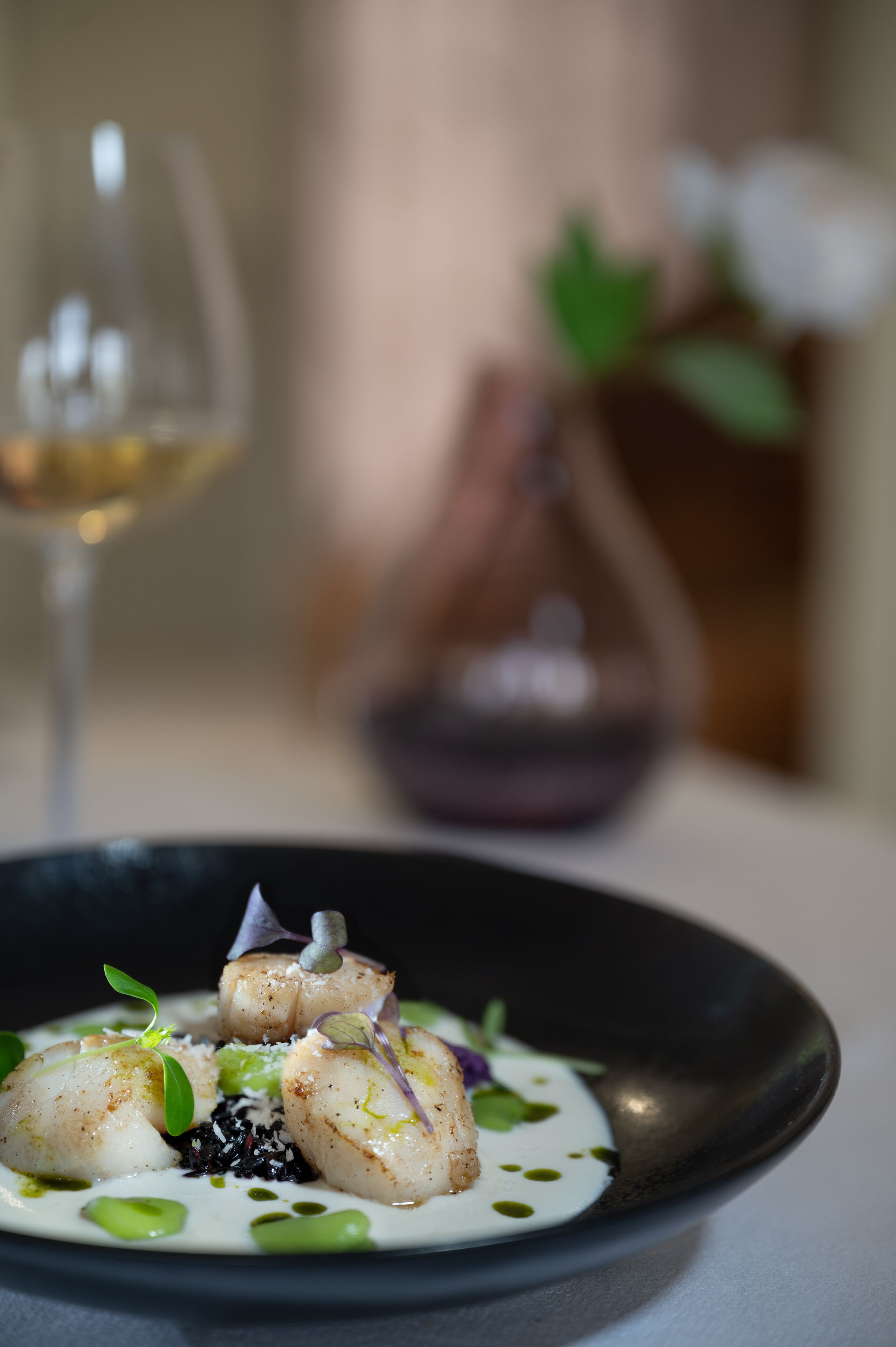 A plate of food with a glass of white wine in the background.