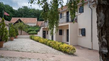 A courtyard with a gravel path, potted plants, and a building with a balcony.