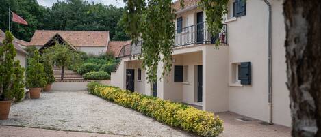 A courtyard with a gravel path, potted plants, and a building with a balcony.