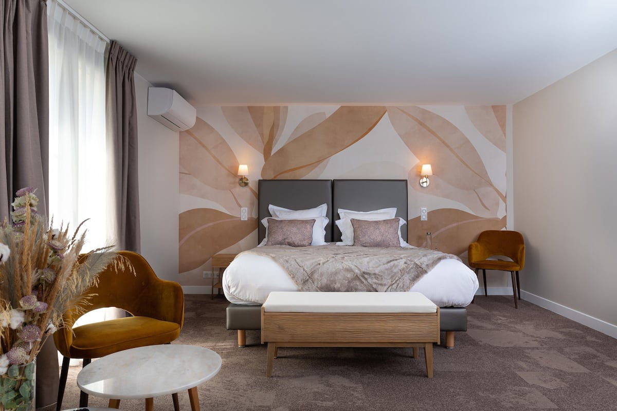 Habitación de hotel moderna con una cama grande, dos mesitas de noche, una pequeña mesa redonda y dos sillas.