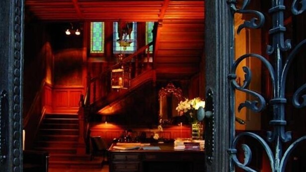 A wooden interior with a staircase, a desk with books, and a decorative vase. - Château La Thuilière (Saint-Front-de-Pradoux)