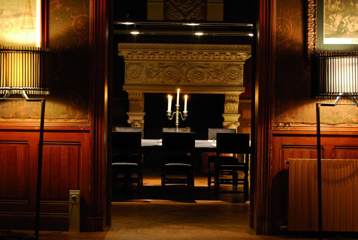 Una habitación ornamentada con chimenea, un candelabro y un piano.