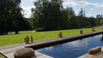 A swimming pool with a wooden deck and stone planters.