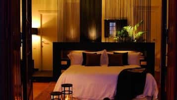 Habitación de hotel con una cama grande, una mesita de noche, una lámpara y vistas al exterior.