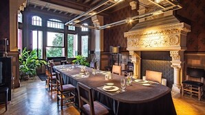 A formal dining room with a long table set for a meal, large windows, and classical architectural details. - Château La Thuilière (Saint-Front-de-Pradoux)