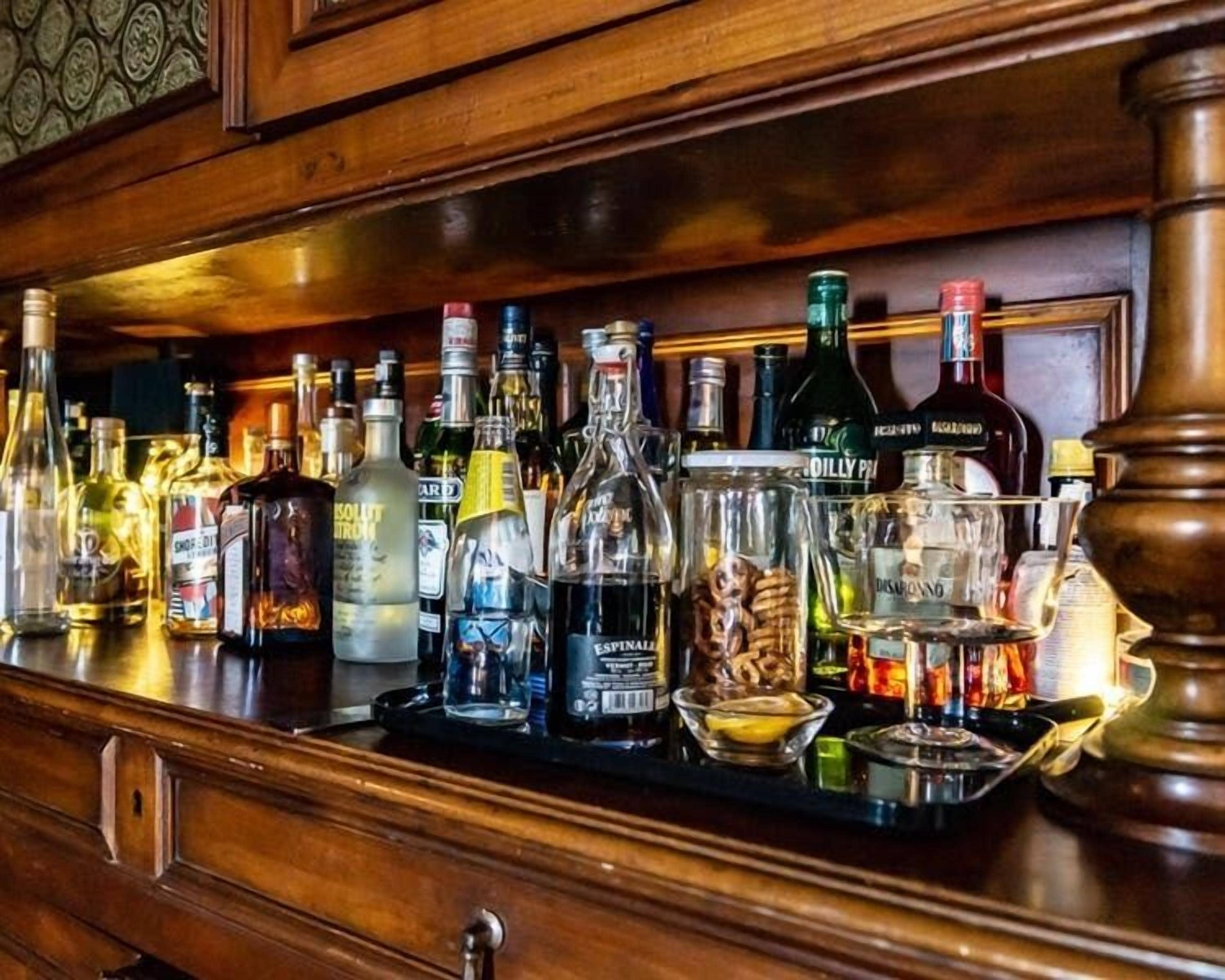 Una barra con diferentes botellas de licor y vasos.