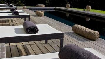 Une terrasse en bois avec des chaises longues et une piscine.