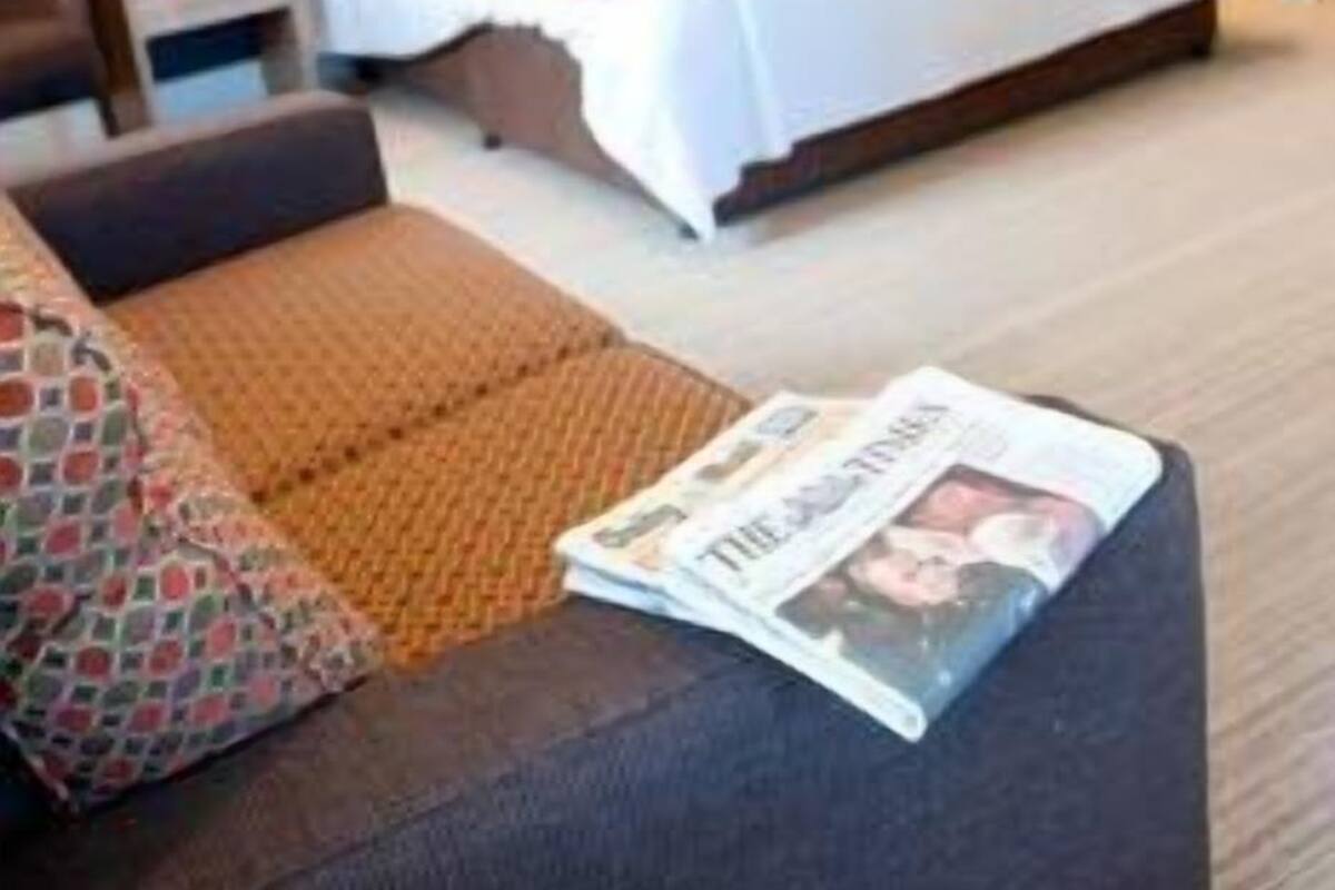 Una habitación de hotel con cama, sofá, mesita de noche y armario.
